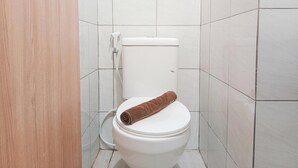 Un baño pequeño y limpio con azulejos blancos, inodoro y zona de ducha.