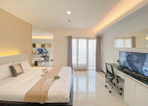 A modern hotel room with a large bed, a desk with a TV, and a balcony with curtains. - Restful And Cozy Studio Tamansari Semanggi Apartment (Jakarta)