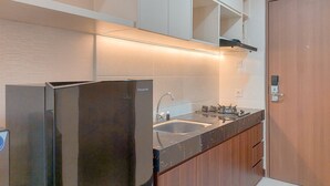 A modern kitchen with a stainless steel refrigerator, a double sink, and wooden cabinets. - Minimalist And Warm Studio Apartment At B Residence (Pagedangan)