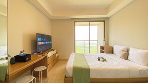 Ein Hotelzimmer mit Bett, Schreibtisch mit Fernseher, Fenster mit Aussicht und einem kleinen Hocker.