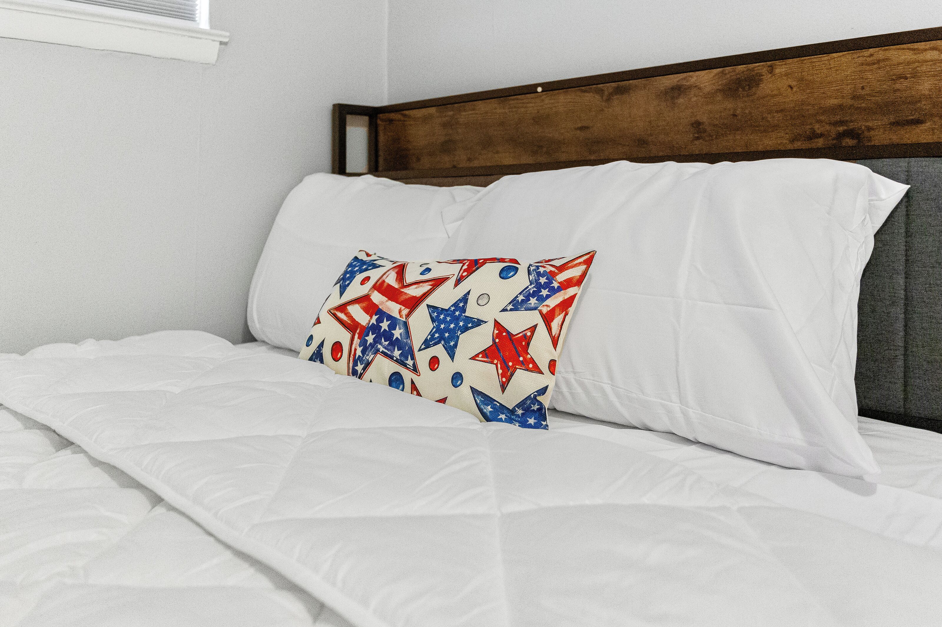 Un lit avec une literie blanche et un oreiller orné d’un motif en forme d’étoile.