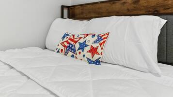 Un lit avec une literie blanche et un oreiller orné d’un motif en forme d’étoile.