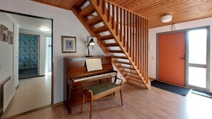 A wooden staircase leading to a second floor, a piano with sheet music, and a door with a view to the outside. - 5 bedroom nice home in Västra Torup (Västra Torup)