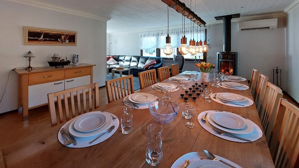 A dining room with a wooden table set for six, surrounded by chairs. A fireplace is visible in the background, and a painting hangs on the wall. - 5 bedroom nice home in Västra Torup (Västra Torup)