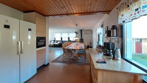 A modern kitchen with built-in appliances, a dining area with a wooden table and chairs, and a view of the outdoors. - 5 bedroom nice home in Västra Torup (Västra Torup)