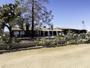 A building with a covered patio area, a fenced garden with cacti, and a clear sky.