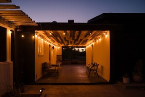 An outdoor covered patio area with string lights, seating, and potted plants.