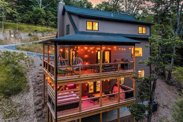 Spacious 3-story cabin glowing warmly among the trees at dusk