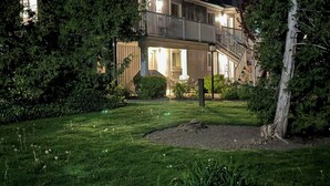 Una casa de dos pisos con balcón, rodeada de árboles y un césped bien cuidado.