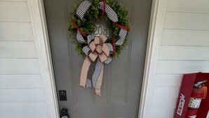 A front door with a wreath, a fire extinguisher, and a welcome sign.