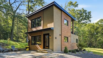 A two-story modern house with a stone patio and outdoor seating.