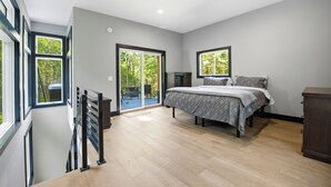 Een slaapkamer met een bed, een dressoir, een bureau en een schuifdeur naar een buitenruimte.