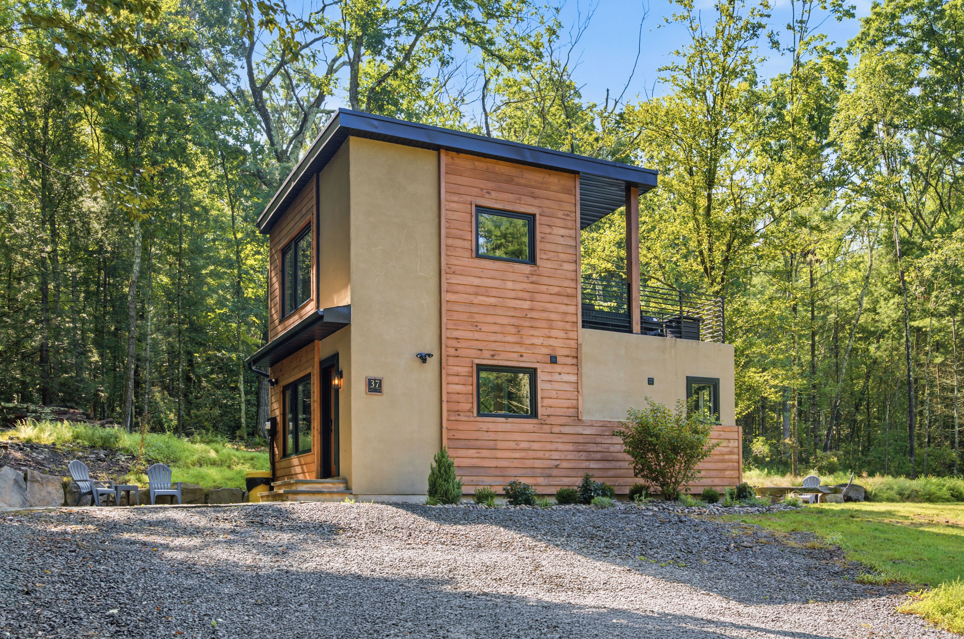 Une cabane moderne à deux étages, dotée d’un toit plat et entourée d’une forêt.