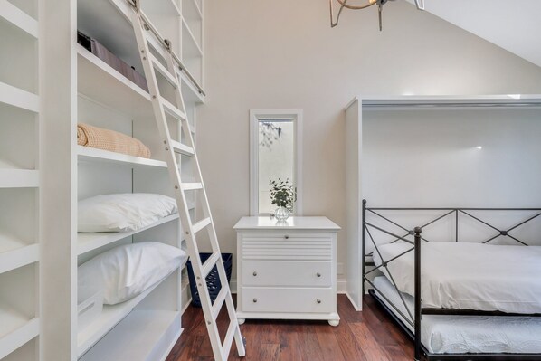 Un dormitorio con una litera, un aparador blanco y una escalera.