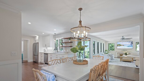 A spacious kitchen with white cabinetry, a central island, and a chandelier.