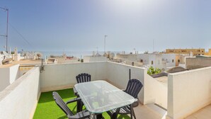 Une terrasse sur le toit, avec une table et des chaises en verre, offrant une vue sur le paysage urbain de la côte.