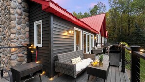 Une terrasse extérieure accueillante, avec un mur en pierre, un toit rouge et un canapé en osier.