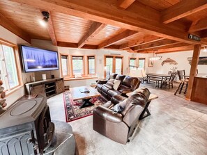 A spacious living room with a fireplace, leather sofa, and a television.