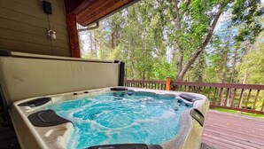 Een hottub op een houten terras met uitzicht op bomen.
