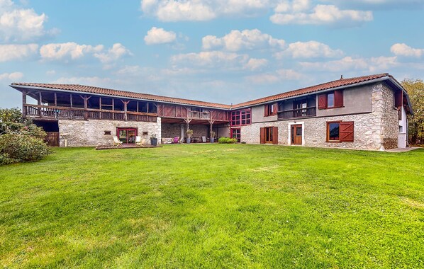 A large stone building with multiple balconies and a spacious lawn.