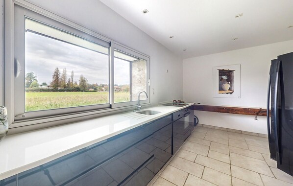 A modern kitchen with a large window, a sink, and a tiled floor.