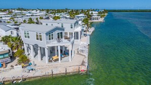 Une propriété située en bord de mer, comprenant une grande maison dotée d’un balcon et d’une terrasse couverte.