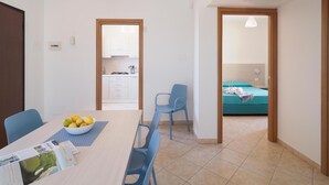 A modern kitchen with white cabinets and a dining area with a table set for two. - 2 bedroom lovely home in Marina di Modica (Marina di Modica)