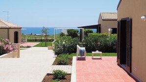 A courtyard with a view of the sea, a pergola, and a small table with chairs. - 2 bedroom lovely home in Marina di Modica (Marina di Modica)