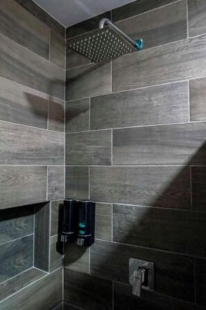 Superior vierpersoonskamer | Badkamer | Een douche, handdoeken, zeep, shampoo