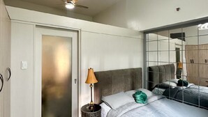 Un dormitorio moderno con cama, lámpara, ventilador de techo y espejo.