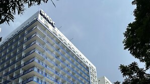 Un hotel de varios pisos con balcones, un estacionamiento y vista a la calle.