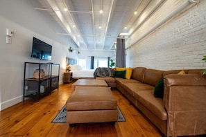 Uma sala de estar moderna com um sofá seccional, uma televisão e um chão de madeira.