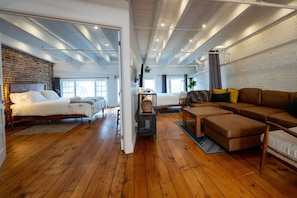 Amplo quarto estilo loft com uma cama grande, um sofá e um espaço para refeições.