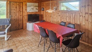 A wooden-paneled room with a dining table, chairs, a TV, and a painting on the wall. - Three bedroom nice home in Løkken (Løkken)
