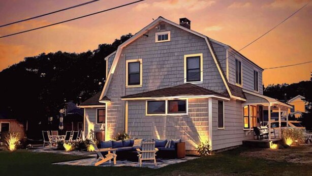 Une maison à deux étages avec un porche, une pelouse et un espace salon extérieur.