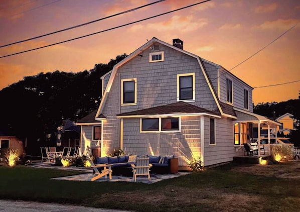 A two-story house with a porch, a lawn, and outdoor seating.