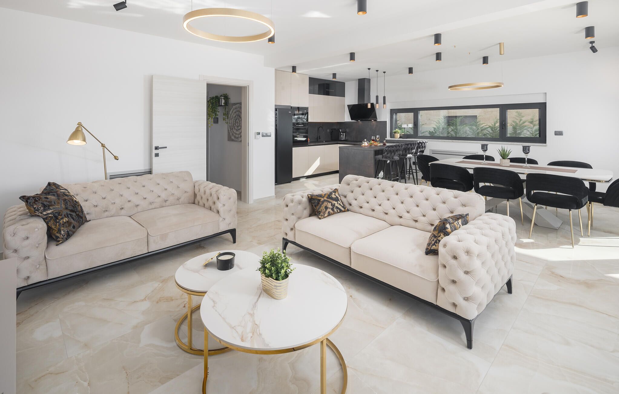 A modern living room with two sofas, a dining area, and a kitchen.