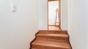 A wooden staircase leading to a room with a wooden door and a white wall.
