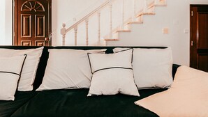 A room with a dark green sofa, white pillows, a wooden door, and a staircase with white balusters. - Altura Beach Villa by GT House (Castro Marim)