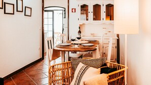 A dining area with a round table set for four, surrounded by wicker chairs. There are framed pictures on the wall and a cabinet with glass doors. - Altura Beach Villa by GT House (Castro Marim)