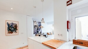 Una cocina moderna con armarios blancos, encimera de madera e iluminación colgante.