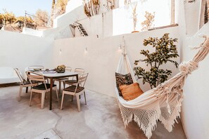 Une terrasse avec une table ronde et des chaises, un hamac et une plante en pot.
