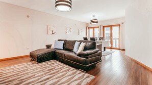 A modern living room with a sectional sofa, a striped rug, and pendant lighting. - Modern & Elegant in Amadora by GT House (Amadora)