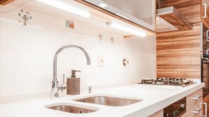 A modern kitchen with a long countertop, stainless steel sink, and built-in stove. - Modern & Elegant in Amadora by GT House (Amadora)