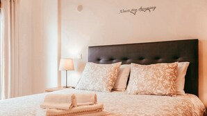 A neatly made bed with a patterned bedspread and pillows, a folded towel, and a wall sign that reads "Never stop dreaming." - Modern & Elegant in Amadora by GT House (Amadora)