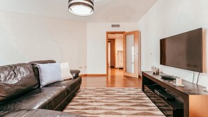 A modern living room with a leather sofa, a flat-screen TV, and a patterned rug. - Modern & Elegant in Amadora by GT House (Amadora)