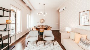 A modern living room with a dining area, featuring a chandelier, a sofa, and a bookshelf. - Elegant & Sophisticated by GT House (Lisbon)