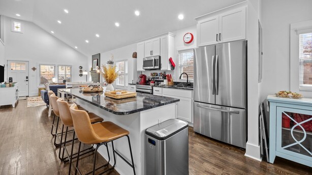 A modern kitchen with a central island, stainless steel appliances, and a dining area with bar stools.