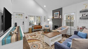 A spacious living room with a flat-screen TV, a fireplace, and a large window.