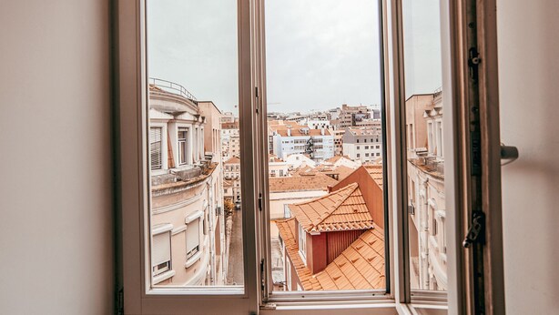 A view through a window of a cityscape with buildings and a distinct red-roofed structure. - Central & Typical Lisboa by GT House (Lisbon)